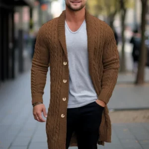 A picture of a man with his left hand in his pocket as he walks wearing a long gents autumn cardigan with a white t-shirt underneath and black slacks